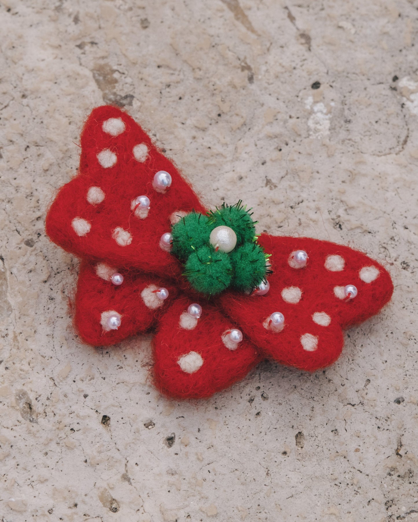 Festive red holiday bow clip with white snowflake dots and delicate pearl accents