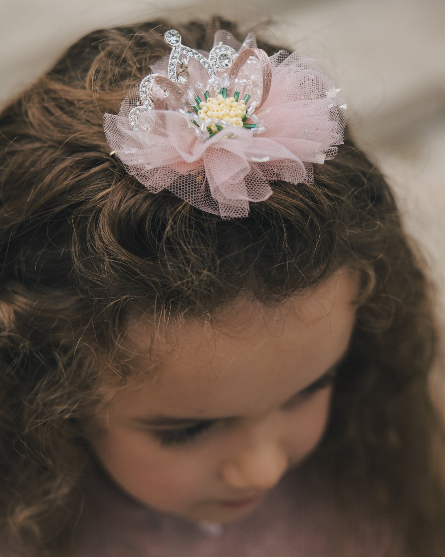 Detailed view of hand-set crystals and layered pink fabric on a princess hair accessory