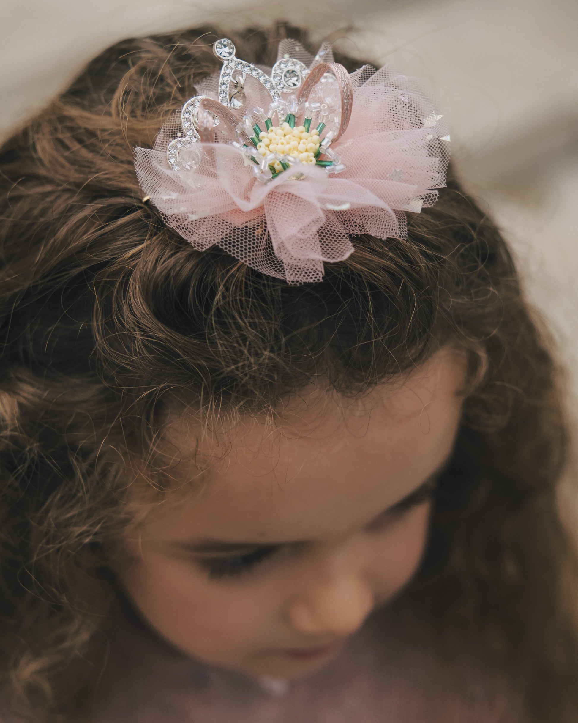 Detailed view of hand-set crystals and layered pink fabric on a princess hair accessory